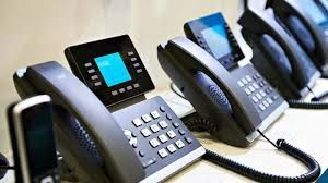 Line of black desk phones with screens and number pads.