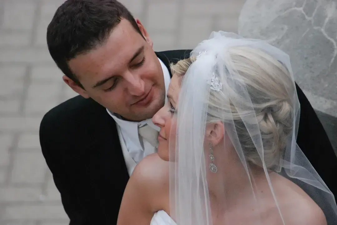 Bride and groom share a close embrace, looking at each other in a tender wedding moment.