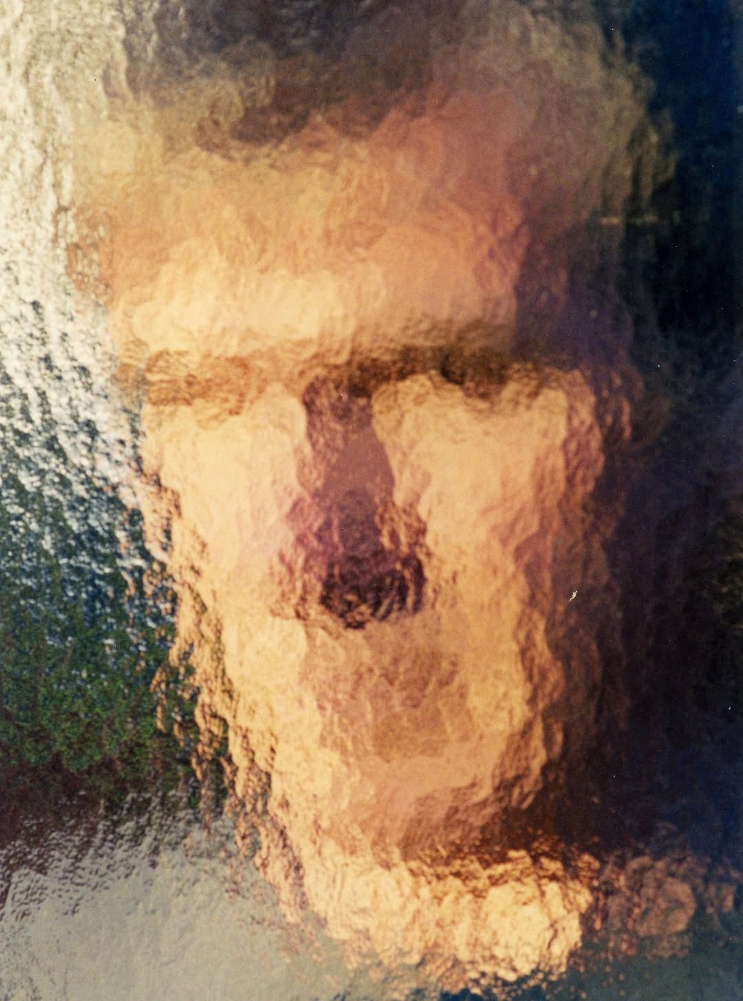 Blurry close-up portrait of a person with a neutral expression in warm light