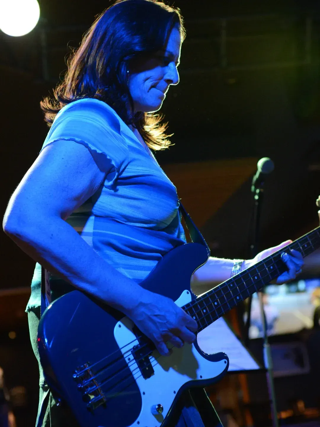 Guitarist under blue stage lights, playing an electric guitar onstage.