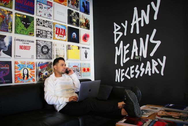 A man is sitting on a couch with a laptop and talking on a cell phone.