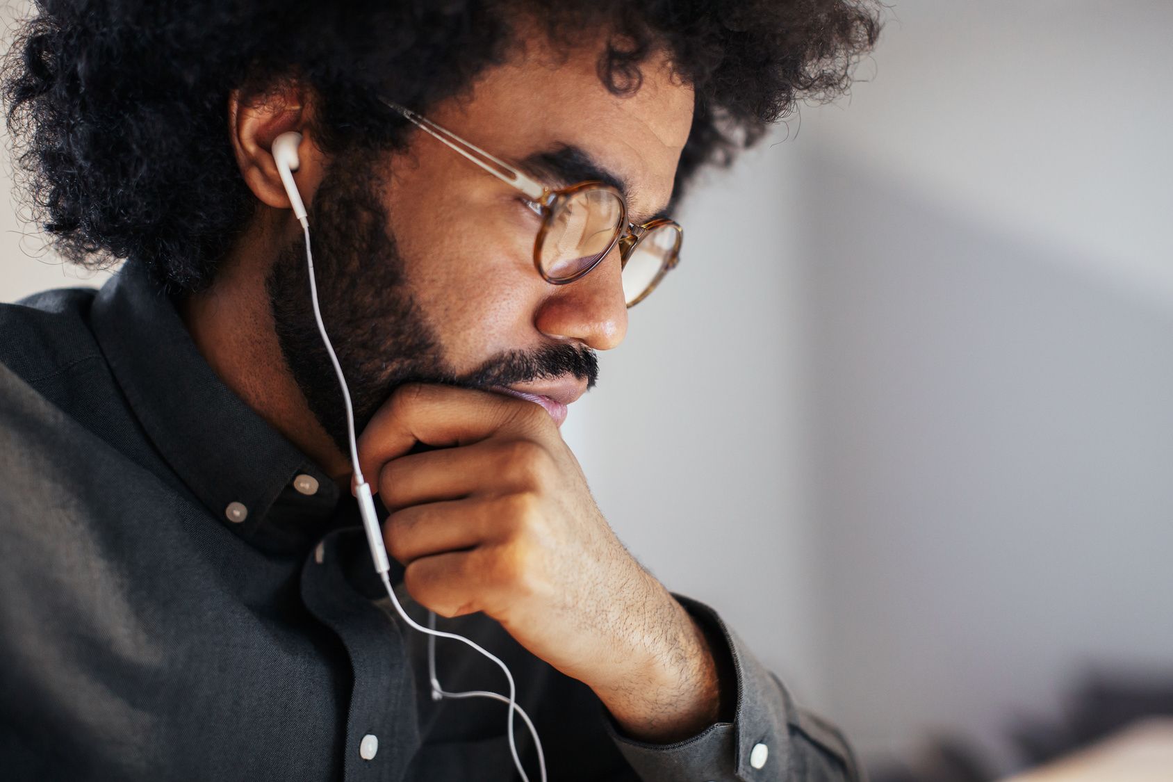 A record label manager wearing glasses and ear buds is listening to a music demo.