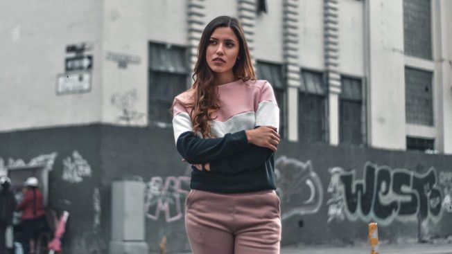 A woman is standing in front of a building with graffiti on it.