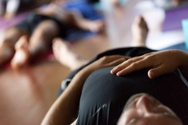 A man is laying on his back with his hands on his chest.