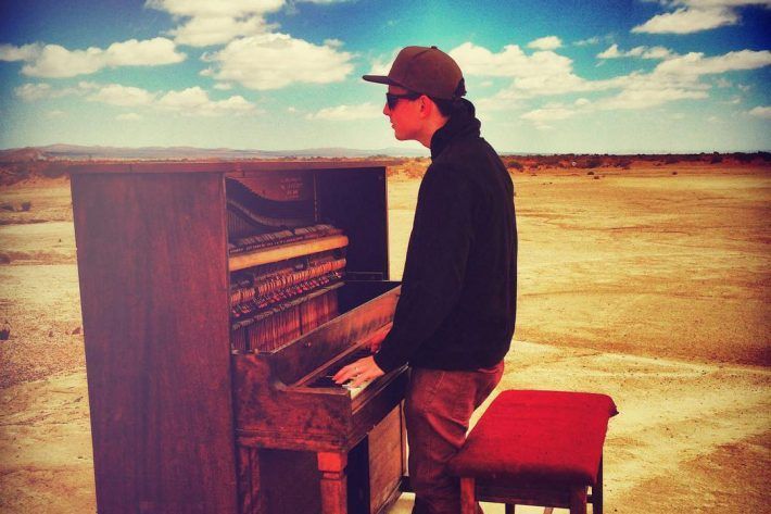 A man is playing a piano in the desert