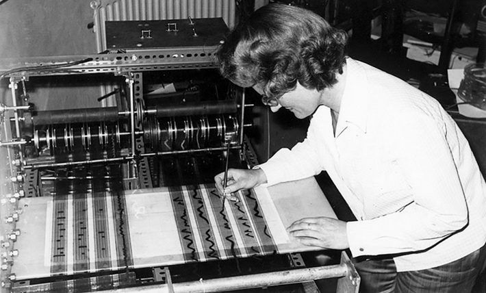 A black and white photo of a woman working on a machine