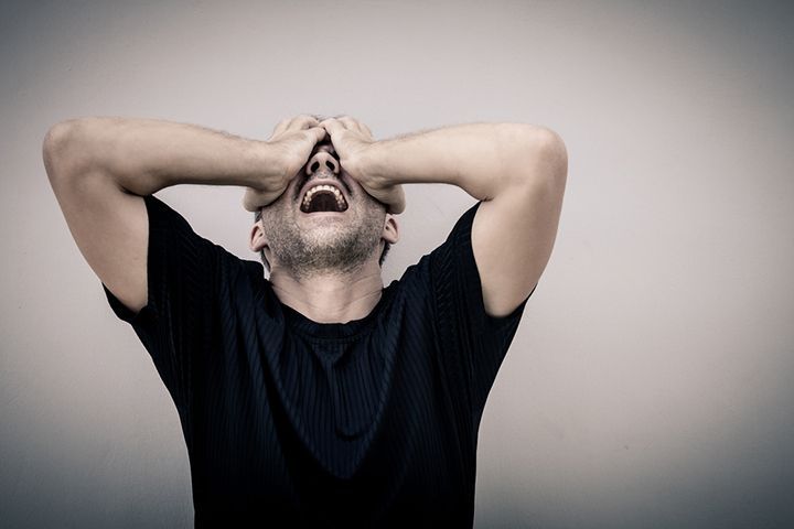 A man is covering his face with his hands and screaming.