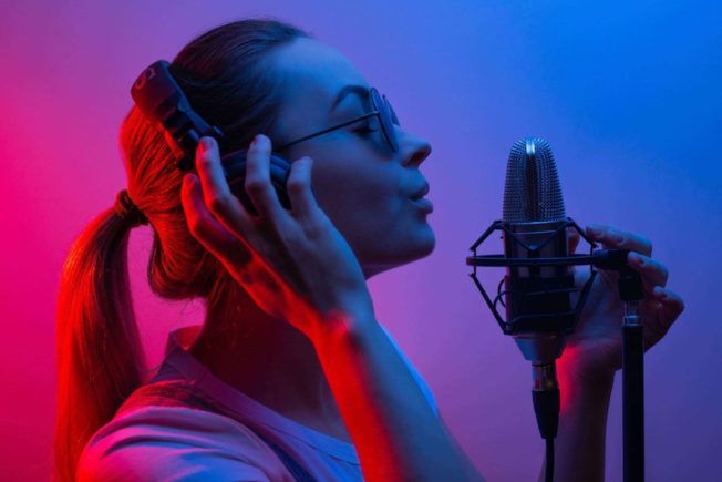 A woman is singing into a microphone practicing her vocal range.