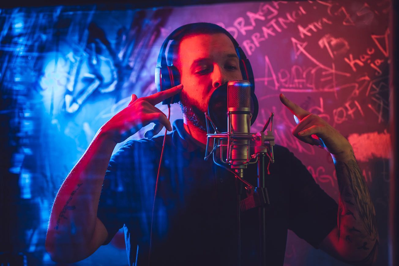 A man wearing headphones is singing into a microphone.