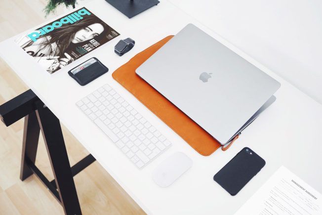 A billboard magazine is on a desk next to a laptop