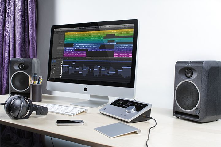 A computer is sitting on a desk next to speakers and headphones.