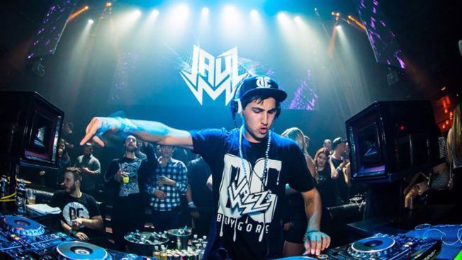 A man is playing music on a stage in a club.