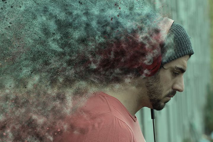 A man wearing headphones and a beanie is listening to music.