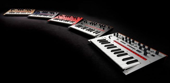 A row of keyboards of different colors are lined up on a table.