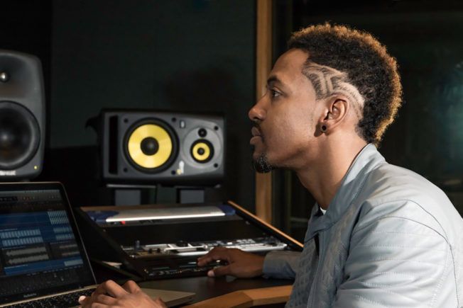 A man is sitting in front of a laptop computer in a recording studio.
