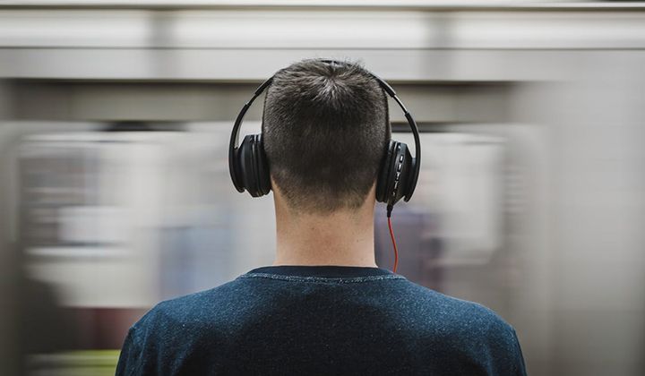 A man wearing headphones is sitting on a train.