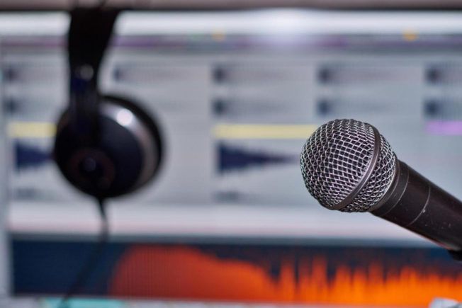 A microphone and headphones are sitting in front of a computer screen.
