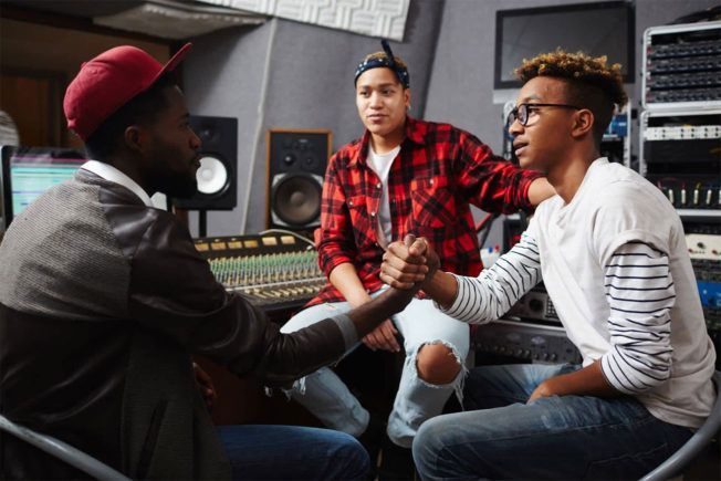 A group of young people are shaking hands in a recording studio.