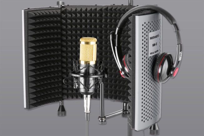 A microphone and headphones are sitting on top of a foam shield.