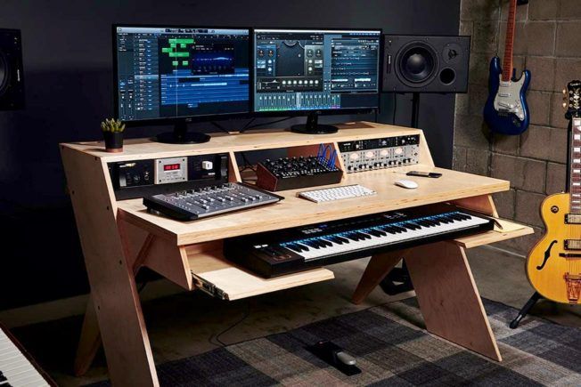 A recording studio with a keyboard , monitors , and a guitar.