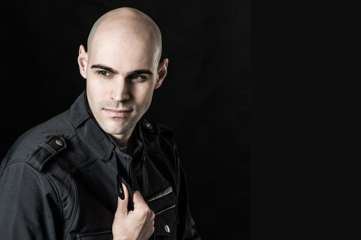 A bald man in a police uniform is adjusting his tie.