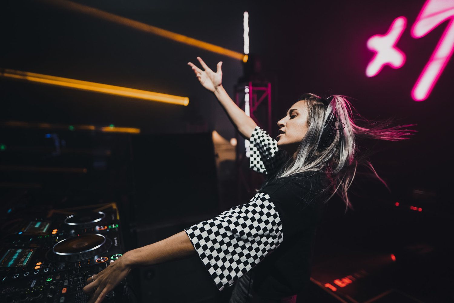 A woman is playing a dj set in a dark room.