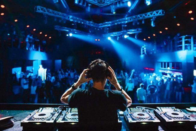 A dj is playing music in front of a crowd at a party.