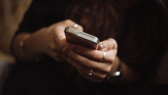 A woman is holding a cell phone in her hands.