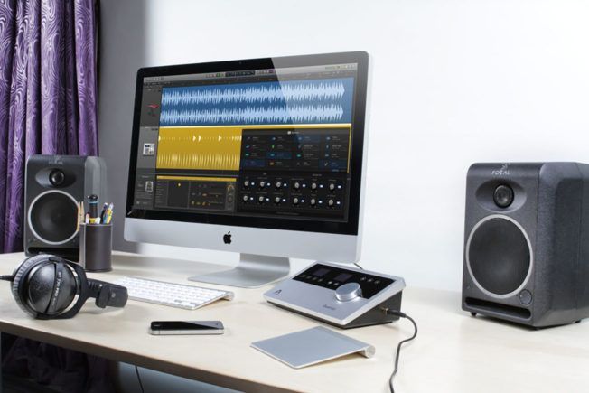 A computer is sitting on a desk next to speakers and headphones.