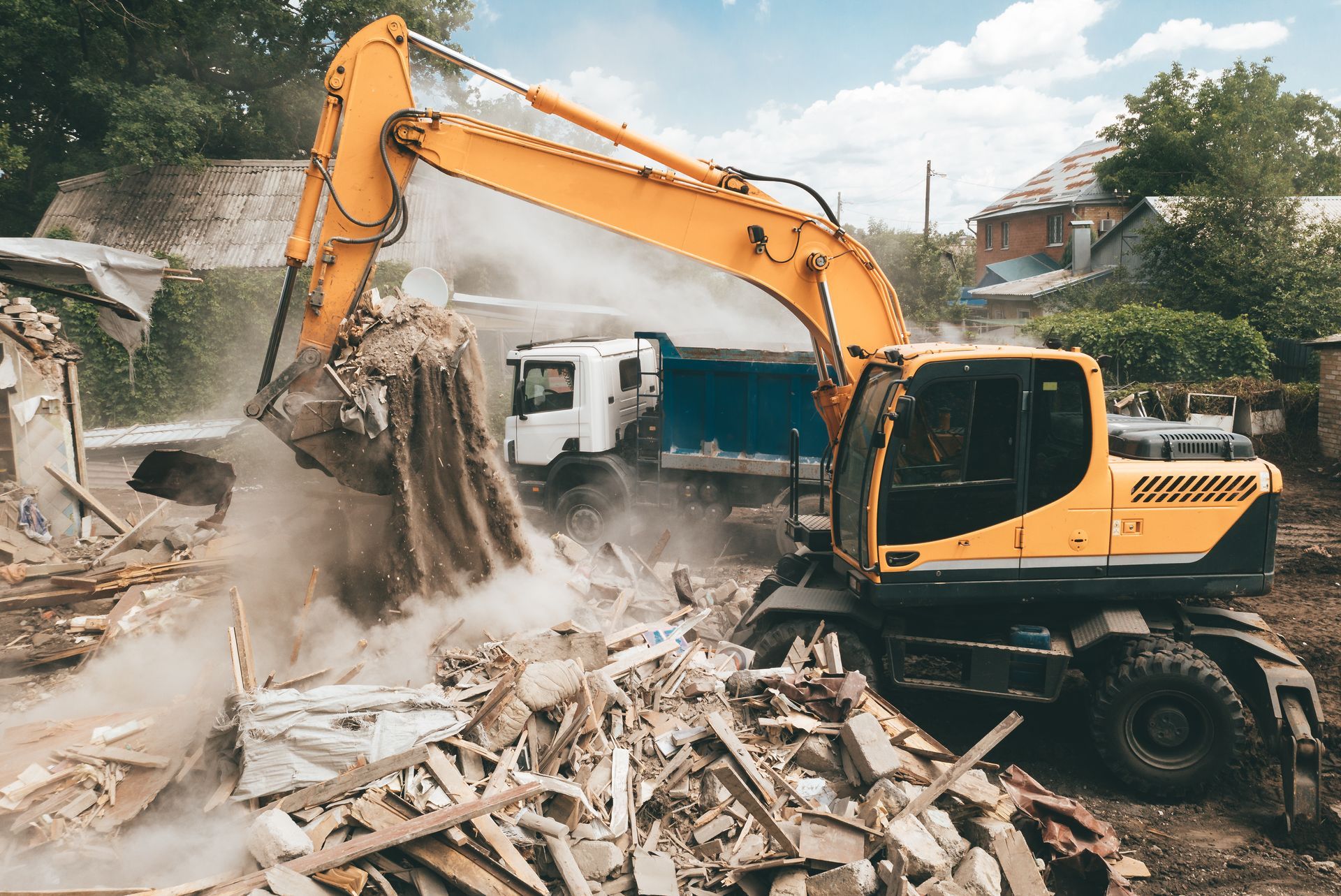 Yellow excavator demolishing a building amid rubble and dust outdoors
