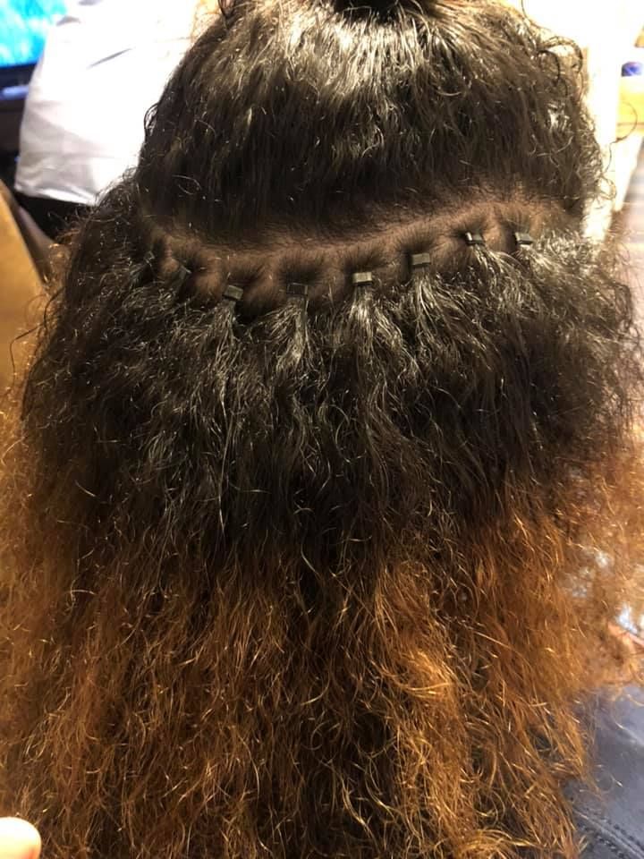 Close-up of dark curly hair sectioned with visible braid rows and lighter brown ends