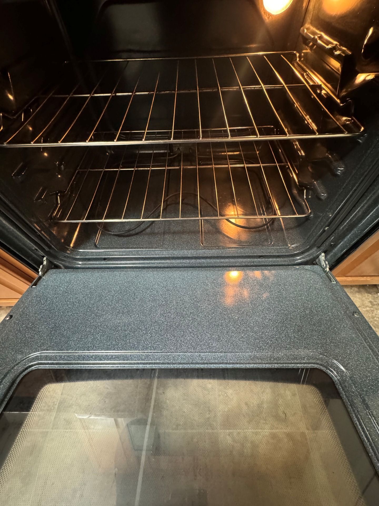 Open oven interior with racks, door open. Lit with interior light.