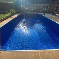 A blue rectangular swimming pool reflecting sunlight.