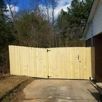 Wooden fence with gate in front of a house, set in a yard.