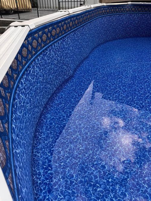 Above ground swimming pool interior with blue patterned liner filled with water.