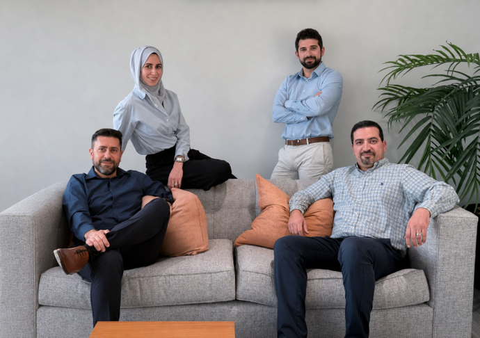 Four doctors smiling leaning over a couch in a bright living room