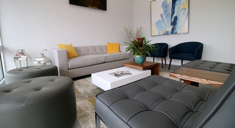 Modern living room with gray sofa, ottoman, coffee table, and blue accent chairs