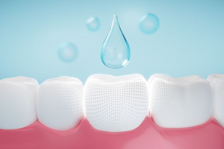 Teeth with water droplets above, suggesting tooth cleaning or oral care with a fresh blue background