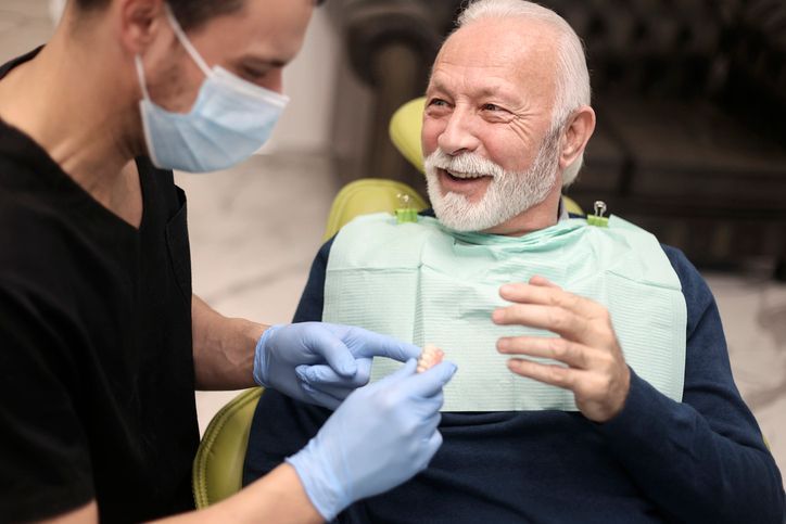 Health care worker in mask and gloves giving an injection to a smiling seated patient