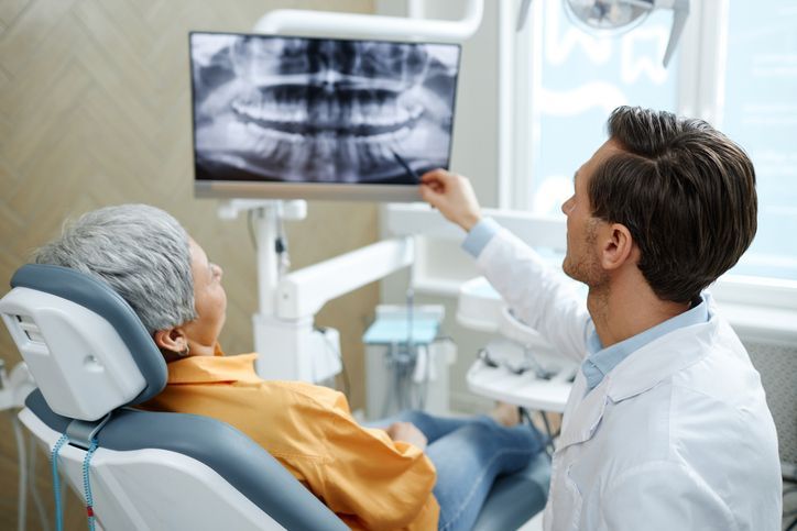 Dentist showing a patient an X-ray on a monitor in a dental clinic