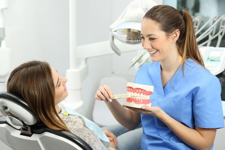 Dentist showing a dental model to a smiling patient in a treatment chair