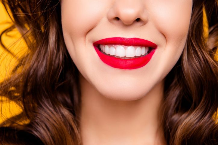 Close-up of a smiling mouth with bright red lipstick and white teeth