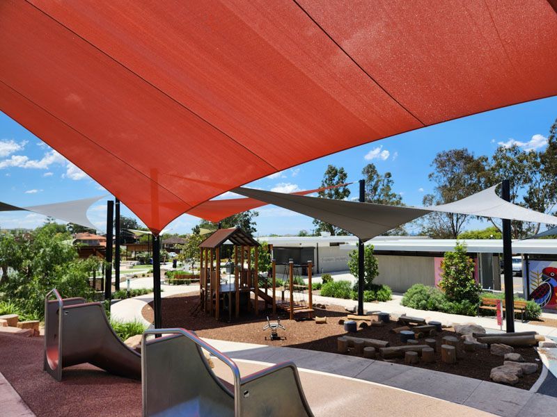 A playground with a slide under an orange umbrella