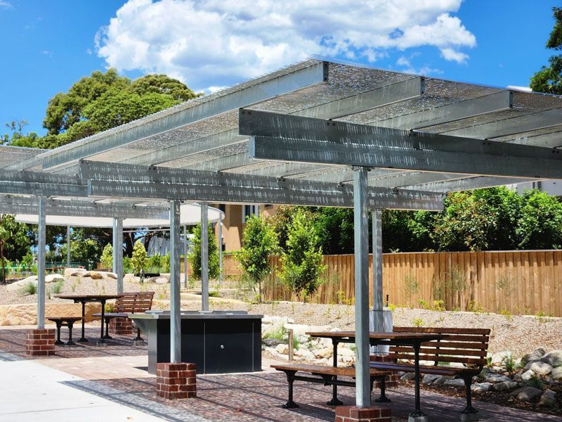A picnic area with tables and benches under a canopy.