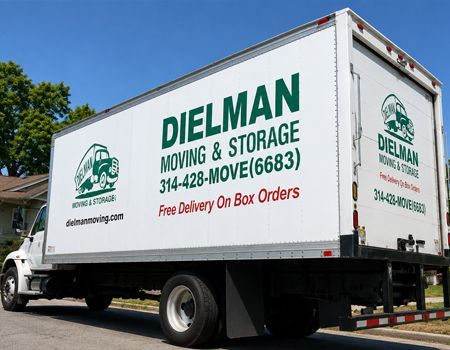 White moving truck with green Dielman Moving & Storage logo and contact info parked outdoors on a sunny day