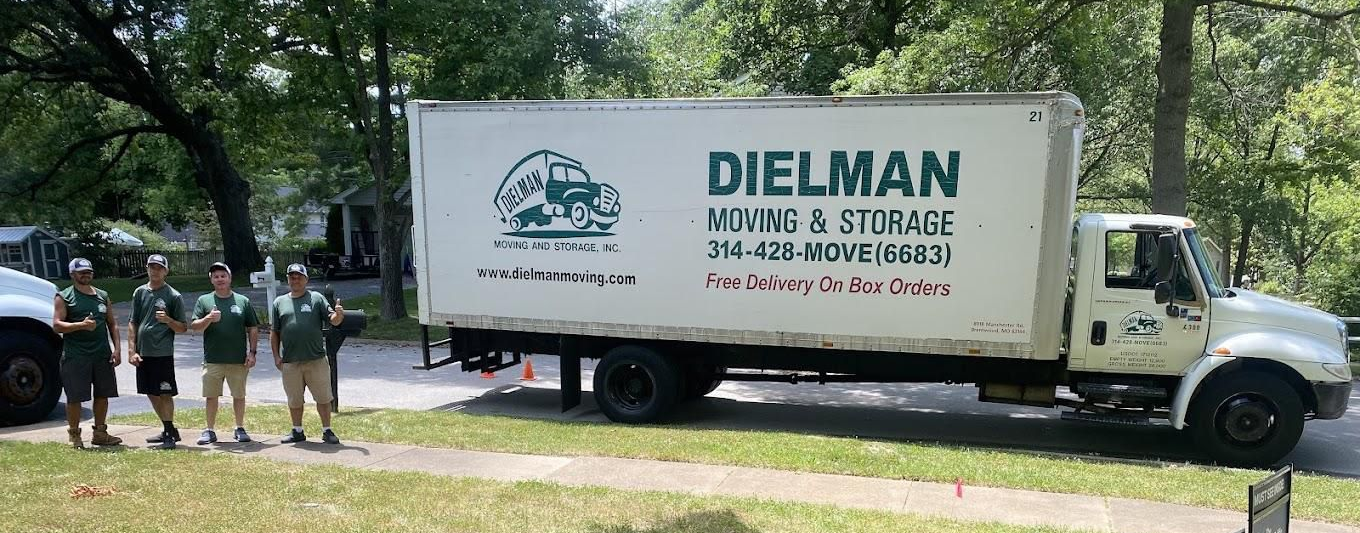 Diehlman moving truck parked by a tree-lined street with people standing nearby