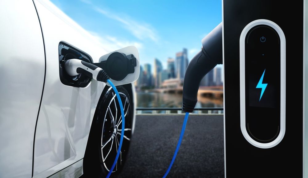 A White Electric Vehicle Charging At A Station — John McEwan Electrical In Dapto, NSW