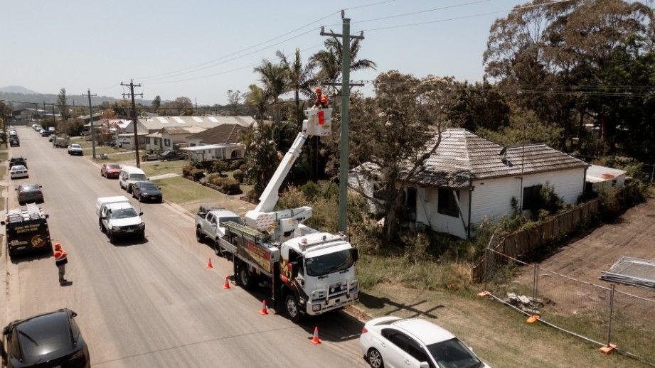 A Truck With a Crane on Top of It is Driving Down a Street — John McEwan Electrical In Dapto, NSW