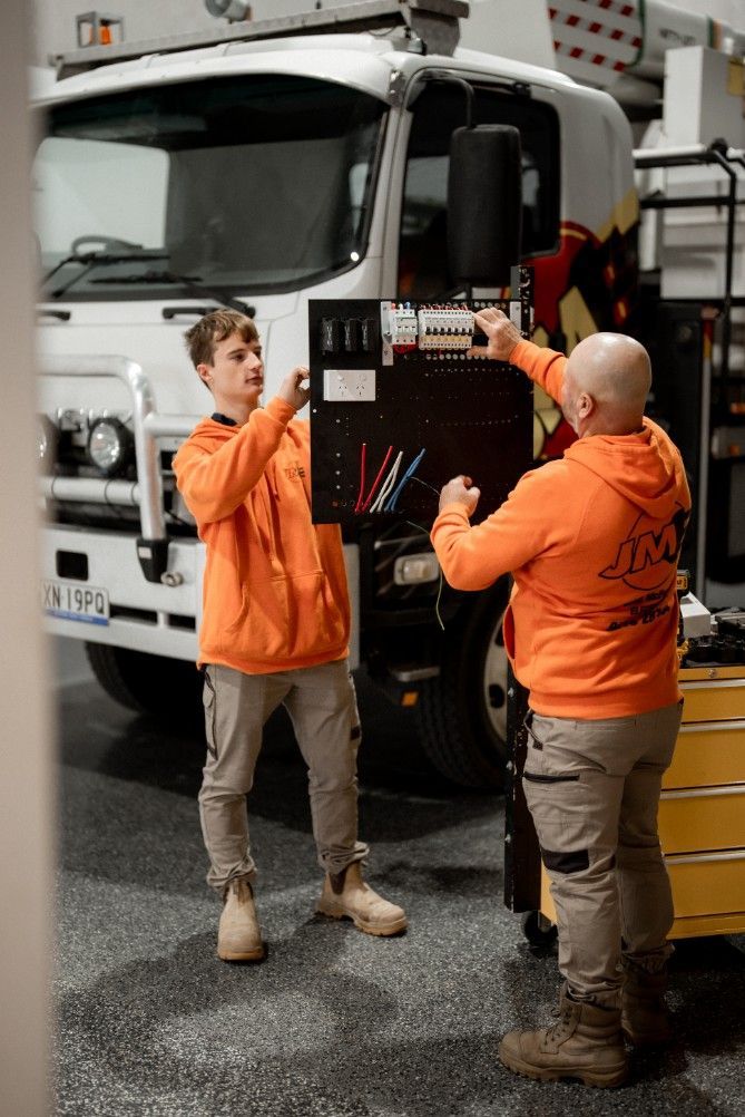 Two Men Are Working on a Truck in a Garage — John McEwan Electrical In Dapto, NSW