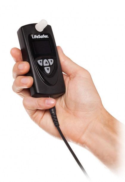 Hand holding a black LifeSafer breathalyzer device with a cord attached